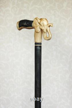 Bâton de marche en bois sculpté avec poignée en forme de tête d'éléphant, de style artisanal.