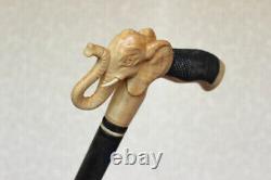 Bâton de marche en bois sculpté avec poignée en forme de tête d'éléphant, de style artisanal.